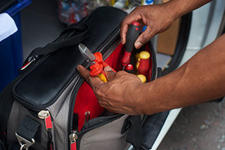 Electrician reaching into tool bag